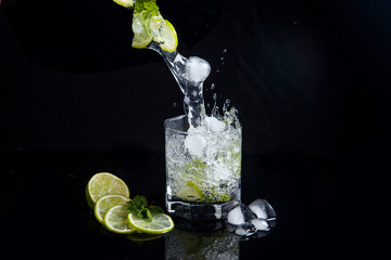 Summer cocktail mojito with splash on black background..
