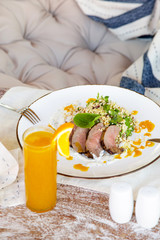 Lamb tenderloin served with barley salad and a glass of fresh squeezed orange juice. Casual-dining restaurant concept.