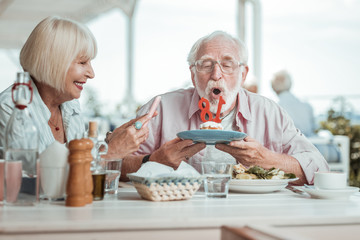 Attentive senior male person staring at candles
