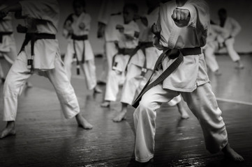 Kids training on karate-do. Banner with space for text. For web pages or advertising printing. Black and white photo without faces. - obrazy, fototapety, plakaty