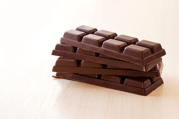 small chocolate bars stacked on each other on a light background