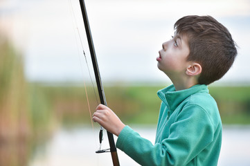 child boy holds fishing rod with wobbler bait
