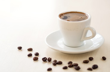 Breakfast. Cup of coffee  and coffee beans on white table