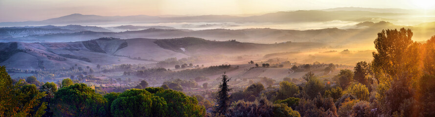 Meadow of Tuscany at misty morning. Rural landscape in fog during sunrise time and hills,