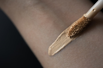 Swatch beige concealer for eyes and skin imperfections on hand, close up. Make-up product