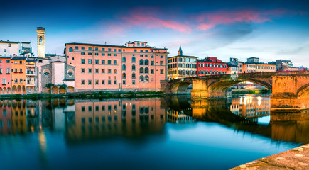 Obraz premium Attractive medieval arched St Trinity bridge (Ponte Santa Trinita) over Arno river. Colorful spring sunset in Florence, Italy, Europe. Traveling concept background.