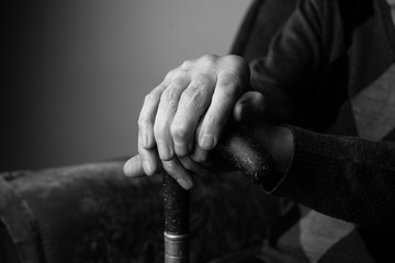 Hands old woman holding cane, skin wrinkled.