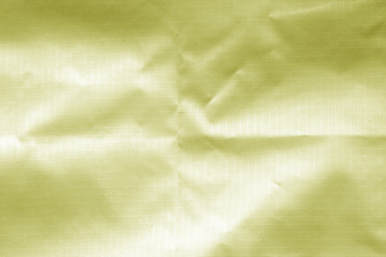 Crumpled transparent plastic surface in yellow color.
