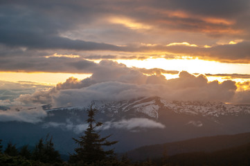 Mountain peak in the clouds and fog at sunset