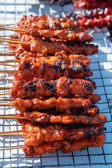 Thai street vendor sells grilled chicken meat at street food market in island Koh Phangan, Thailand. Closeup