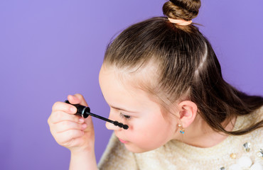 Transforming her eyes with the power of mascara. Small child using mascara brush for enhancing eyelashes. Little girl applying eye mascara. Cute baby doing her eye makeup with black mascara