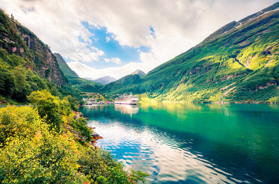 Sunny summer scene of Geiranger port, western Norway. Splendid morning view of Sunnylvsfjorden fjord. Traveling concept background. Artistic style post processed photo.
