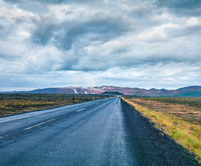 Empty asphalt road with colorful cloudy sky. Beautiful outdoor scenery in the Hverarond geothermal...