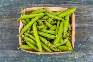 Green pea pods on wooden background.