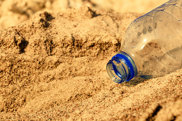 water flows out of a plastic bottle on the sea sand. water saving. last water drop .