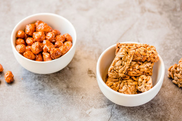Gozinaki bars (Georgian Christmas confection) made of sunflower seeds and honey. Peanuts in sugar in white bowl and on gray background.