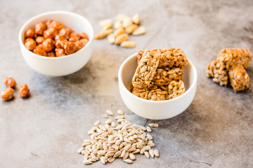 Gozinaki bars (Georgian Christmas confection) made of sunflower seeds and honey. Peanuts in sugar in white bowl and on gray background.