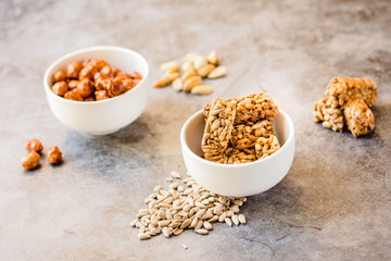 Gozinaki bars (Georgian Christmas confection) made of sunflower seeds and honey. Peanuts in sugar in white bowl and on gray background.