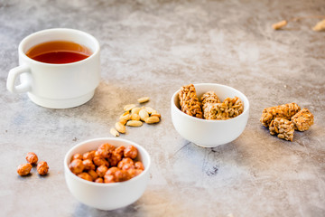Gozinaki bars (Georgian Christmas confection) made of sunflower seeds and honey. Peanuts in sugar in white bowl and on grey background.Sweet dessert snack concept