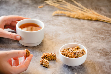 Dessert bars made of sunflower seeds  in a honey caramel. Gozinaki - traditional Georgian confection. Caramelized peanuts in white bowl and on gray background.