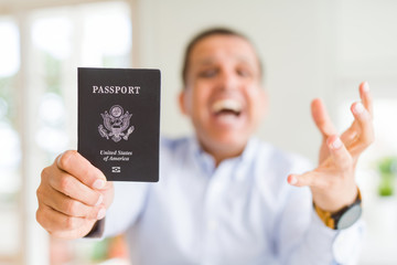 Middle age man holding holding passport of United States very happy and excited, winner expression celebrating victory screaming with big smile and raised hands