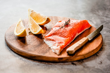 Raw salmon fillets pepper salt dill lemon and rosemary on a wooden board. Prepere for baking.