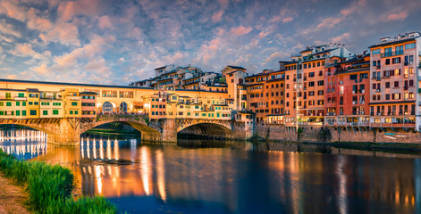 Splendid medieval arched river bridge with Roman origins - Ponte Vecchio over Arno river. Colorful spring sunset view of Florence, Italy, Europe. Traveling concept background.