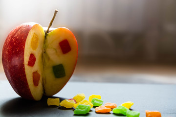 The apple with a candied fruit inside. Close up view on the side of Incised apple. Pieces of candied fruits are around.