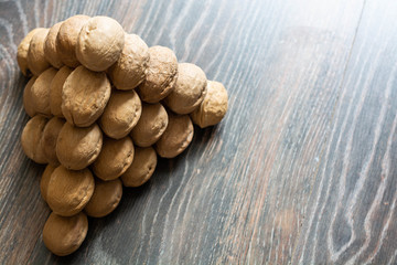 Pyramid of walnuts. Closeup view from top. Walnuts are on the wooden surface. Macrophotography.