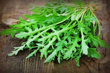 Fresh green arugula leaves on wooden rustic background . Rocket salad or rucola, healthy food, diet. Nutrition concept