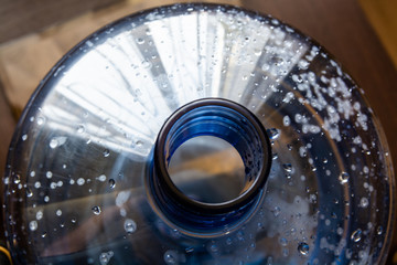 Top view on the big plastic bottle. Empty bottle for water cooler. Drops is on the walls of the bottle.