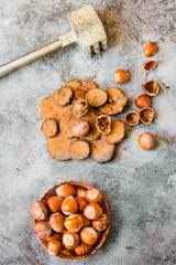 Hazelnuts in the shell in a small wooden and nutcracker. On a gray background. Top view.