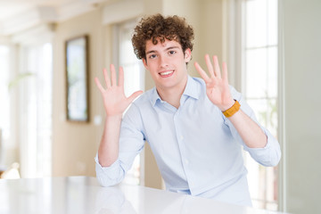 Young business man with curly read head showing and pointing up with fingers number nine while smiling confident and happy.
