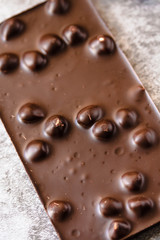 Dark chocolate with hazelnuts in the shel on gray backgroundl, closeup.