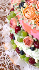 Vintage cake with cream rose flowers and fruits on a table