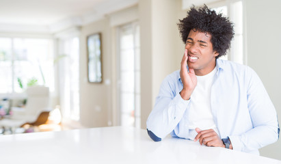 African American man at home touching mouth with hand with painful expression because of toothache...