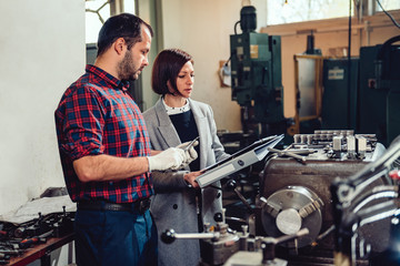Female engineer consulting with machinist using caliper