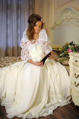 beautiful girl in a long white dress sitting on the bed
