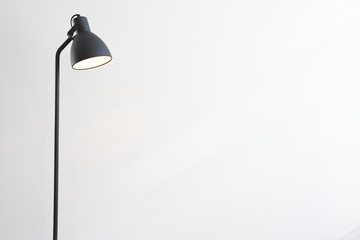 Standing black lamp over white wall