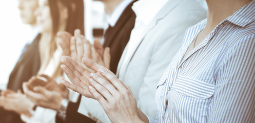 Business people clapping and applause at meeting or conference, close-up of hands. Group of unknown businessmen and women in modern white office. Success teamwork or corporate coaching concept
