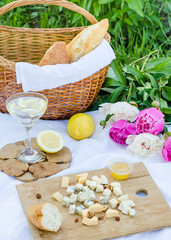 Picnic in the meadow. Cheese, baguette, lemon, fresh water and basket. Close up