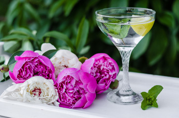 Mojito and summer  flowers. Beautiful flat lay with water with mint and lemon and peonies. Close up