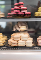 The seller puts delicious French desserts macaroons on the window in his cafe. Very sweet summer dessert of different colors.