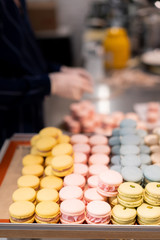 The seller puts delicious French desserts macaroons on the window in his cafe. Very sweet summer dessert of different colors.