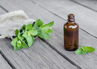Natural Mint Essential Oil in a Glass Bottle with Fresh Mint Leaves