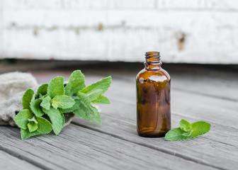 Natural Mint Essential Oil in a Glass Bottle with Fresh Mint Leaves