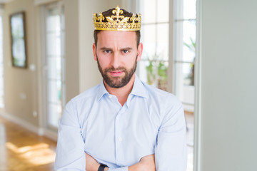 Handsome business man wearing golden crown as a king or prince skeptic and nervous, disapproving expression on face with crossed arms. Negative person.