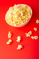 plate with popcorn on a red bright background. movie viewing concept, weekend getaway, with space