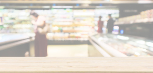 Empty wood table top with abstract supermarket aisle interior blurred defocused background with bokeh light