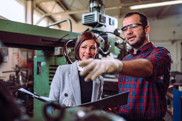 Machinist discussing with female supervisor at factory